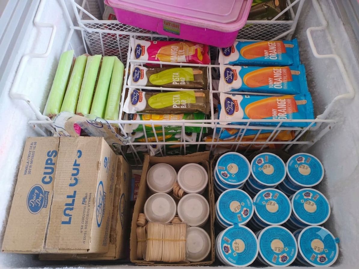Freezer stocked with ice cream tubs, candy bars and cups